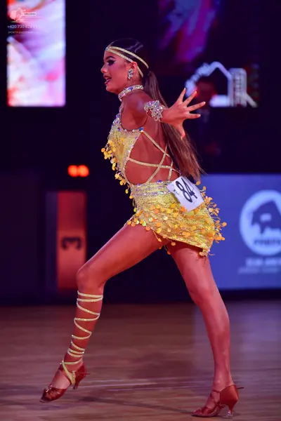 Dancesport competitor: Female dancer: yellow latin dress covered in sequins with petal-like fringe deta