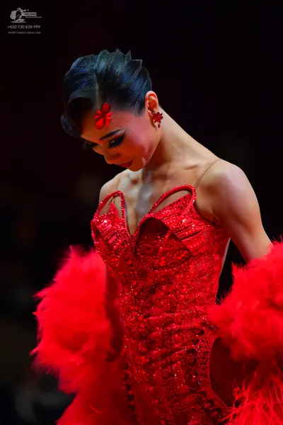 Dancesport competitor: Female dancer: red sequined latin dress with red feathers, red hair accessory, a