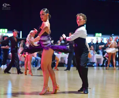 Dancesport competitor: Main female dancer: dark purple or black latin dress with sequins and fringe