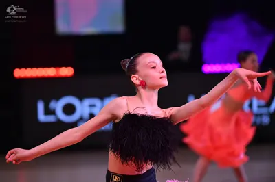 Dancesport competitor: Female dancer in foreground: black Latin dance top with heavy black fringe
