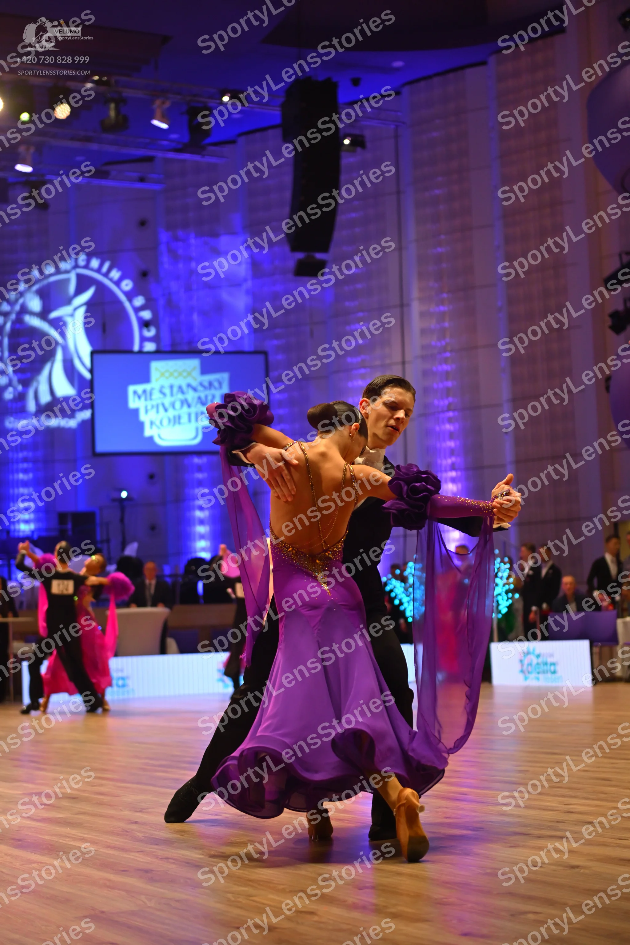 Dancesport competitor: Main female dancer: purple ballgown with a sequin bodice and long, sheer, flowin