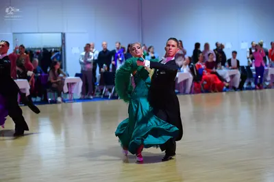 Dancesport competitor: Female dancer: emerald green satin ballgown with voluminous, ruffled sleeves