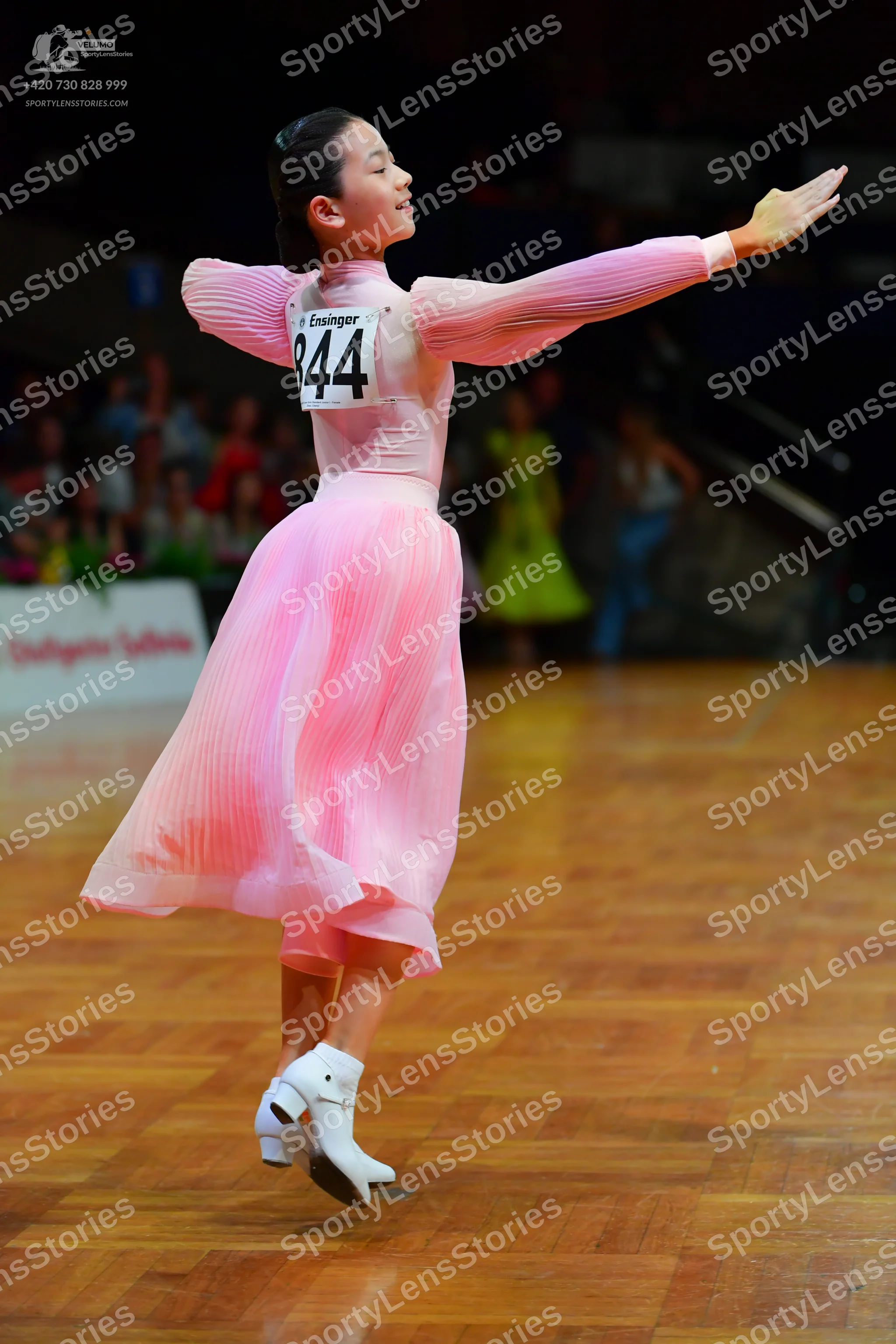 Dancesport competitor: Female dancer: long-sleeved light pink dress with a pleated skirt and white danc