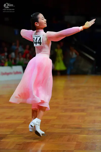 Dancesport competitor: Female dancer: long-sleeved light pink dress with a pleated skirt and white danc