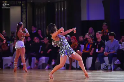 Dancesport competitor: Female dancer in foreground: silver sequined Latin dance dress with fringe