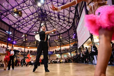 Dancesport competitor: Foreground dancer: pink sequin skirt with pink feather/fringe trim and beaded wa