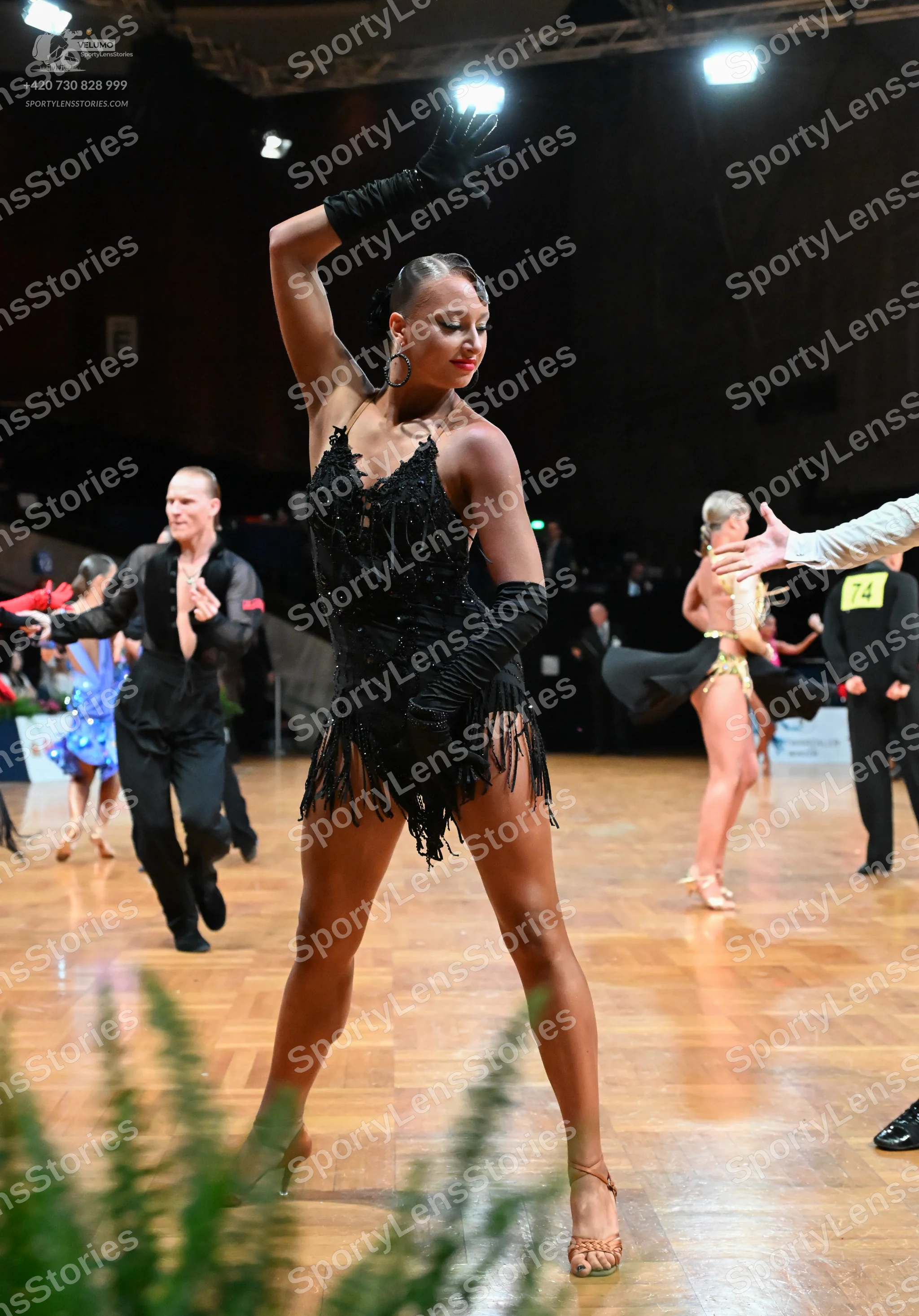 Dancesport competitor #74: Female dancer in foreground: black sequin Latin dress with fringe, long black gl
