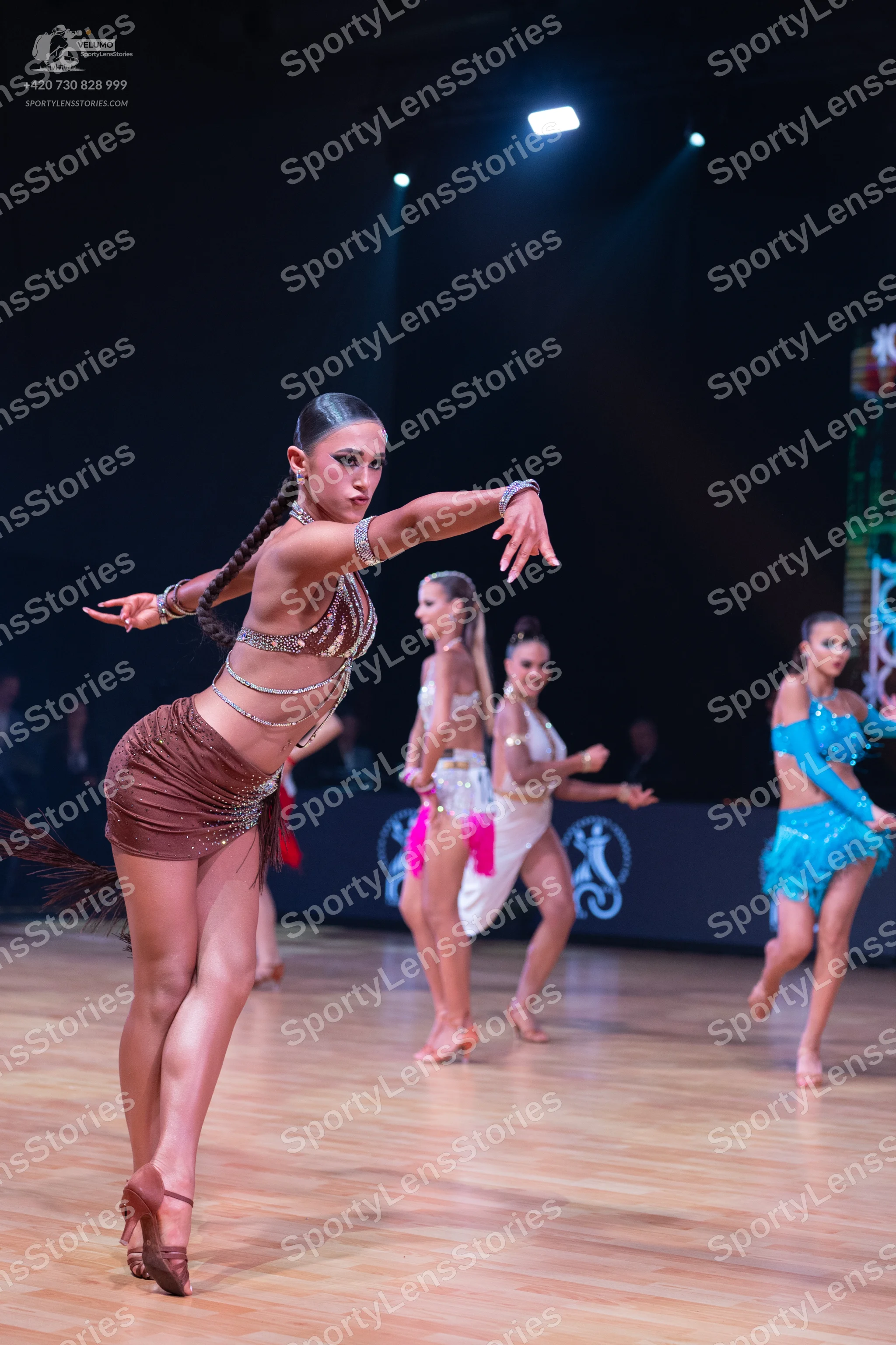 Dancesport competitor: Female dancer in foreground: bronze/brown sequined latin dress with thin straps