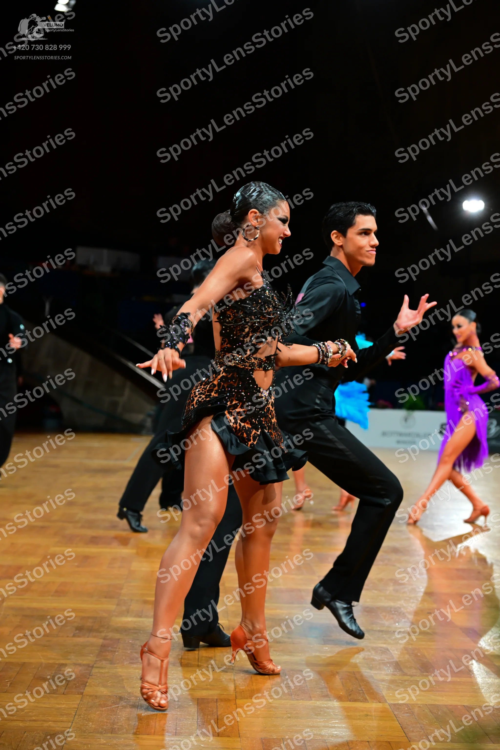 Dancesport competitor: Female dancer in foreground: leopard print Latin dress with black ruffled hem an