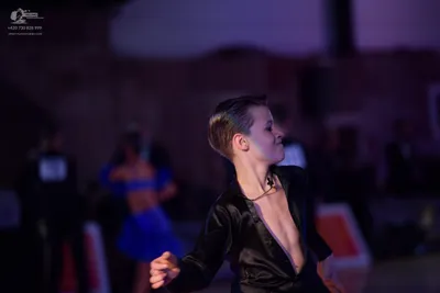 Dancesport competitor: Foreground dancer: black satin-like long-sleeved shirt, open at the chest