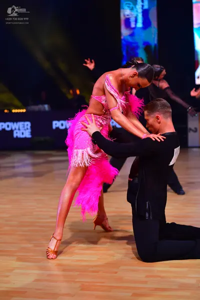 Dancesport competitor: Female dancer: bright pink Latin dance dress with fringe and sequins