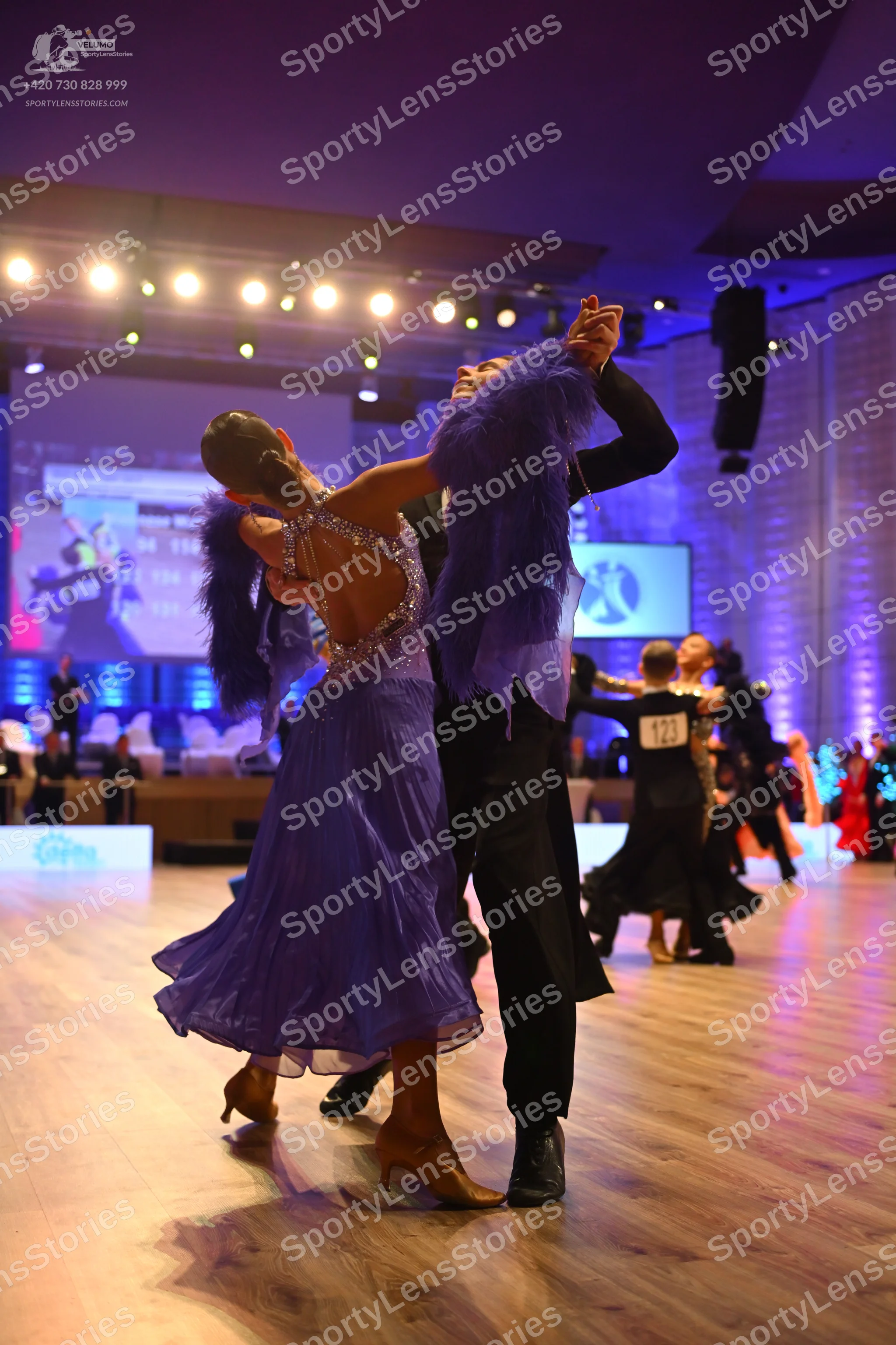 Dancesport competitor: Female dancer (foreground): lavender ballroom dress with a sequined/crystal bodi
