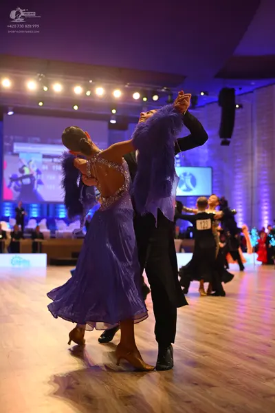 Dancesport competitor: Female dancer (foreground): lavender ballroom dress with a sequined/crystal bodi