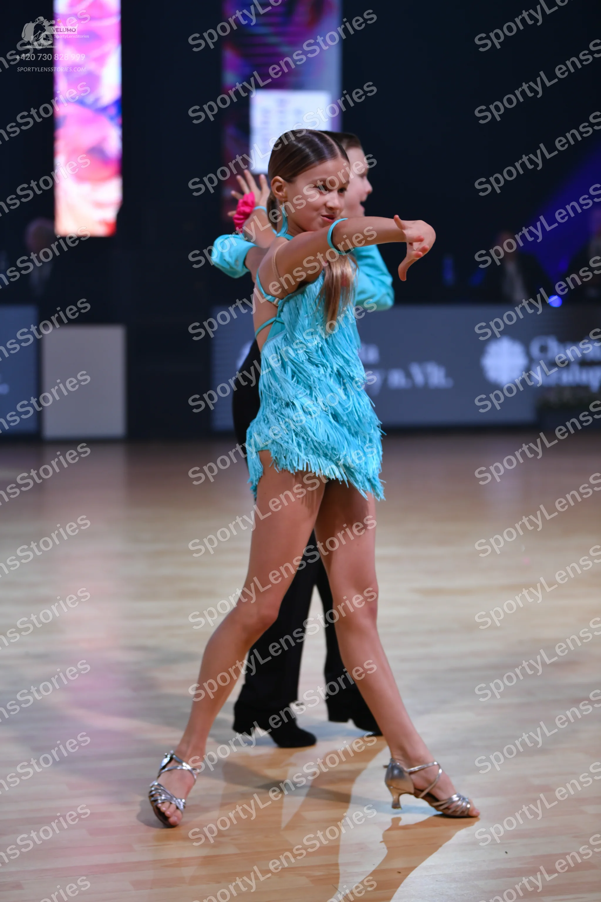 Dancesport competitor: Female dancer: light blue Latin dress with fringe and straps, silver metallic da