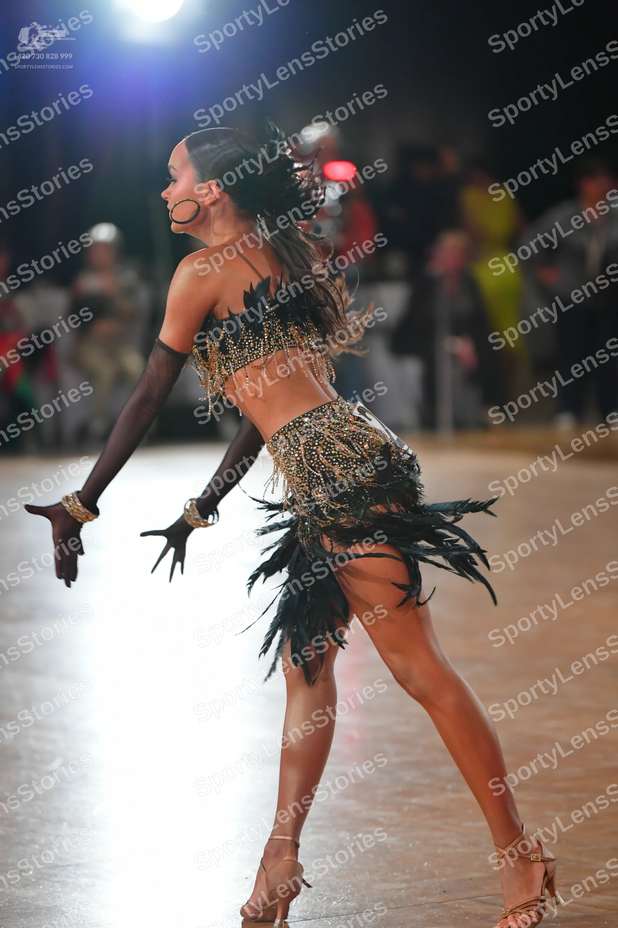 Dancesport competitor: Female dancer: black and gold Latin dance costume featuring a sequined top and a
