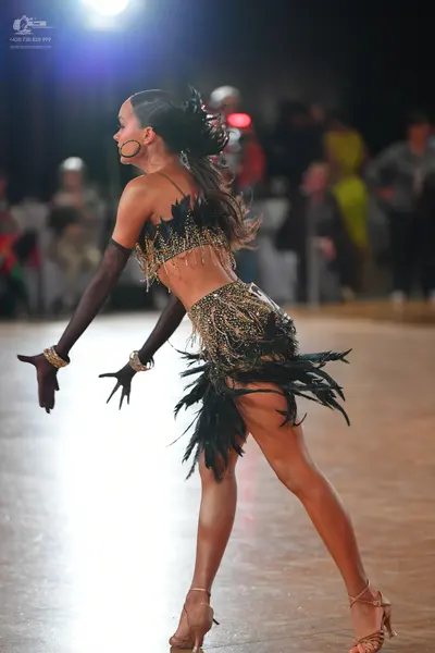 Dancesport competitor: Female dancer: black and gold Latin dance costume featuring a sequined top and a