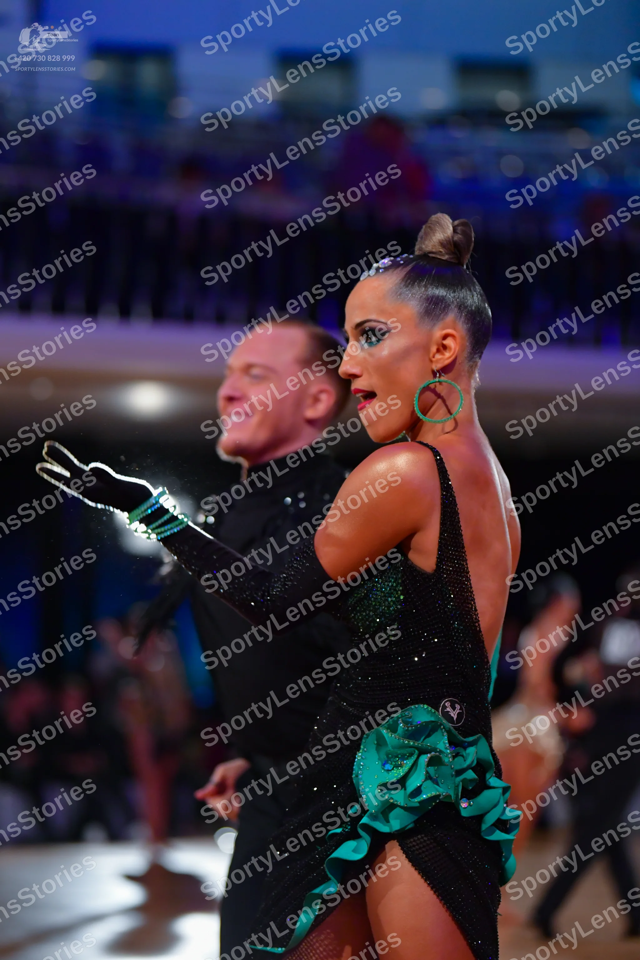 Dancesport competitor: Female dancer: black latin dress with teal ruffles and sequins, long black glove