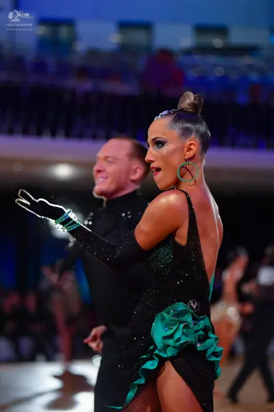 Dancesport competitor: Female dancer: black latin dress with teal ruffles and sequins, long black glove