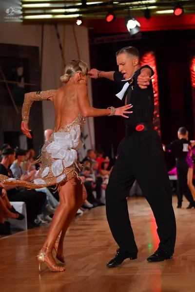 Dancesport competitor: Male dancer: black long-sleeved shirt and black trousers with a red detail at th