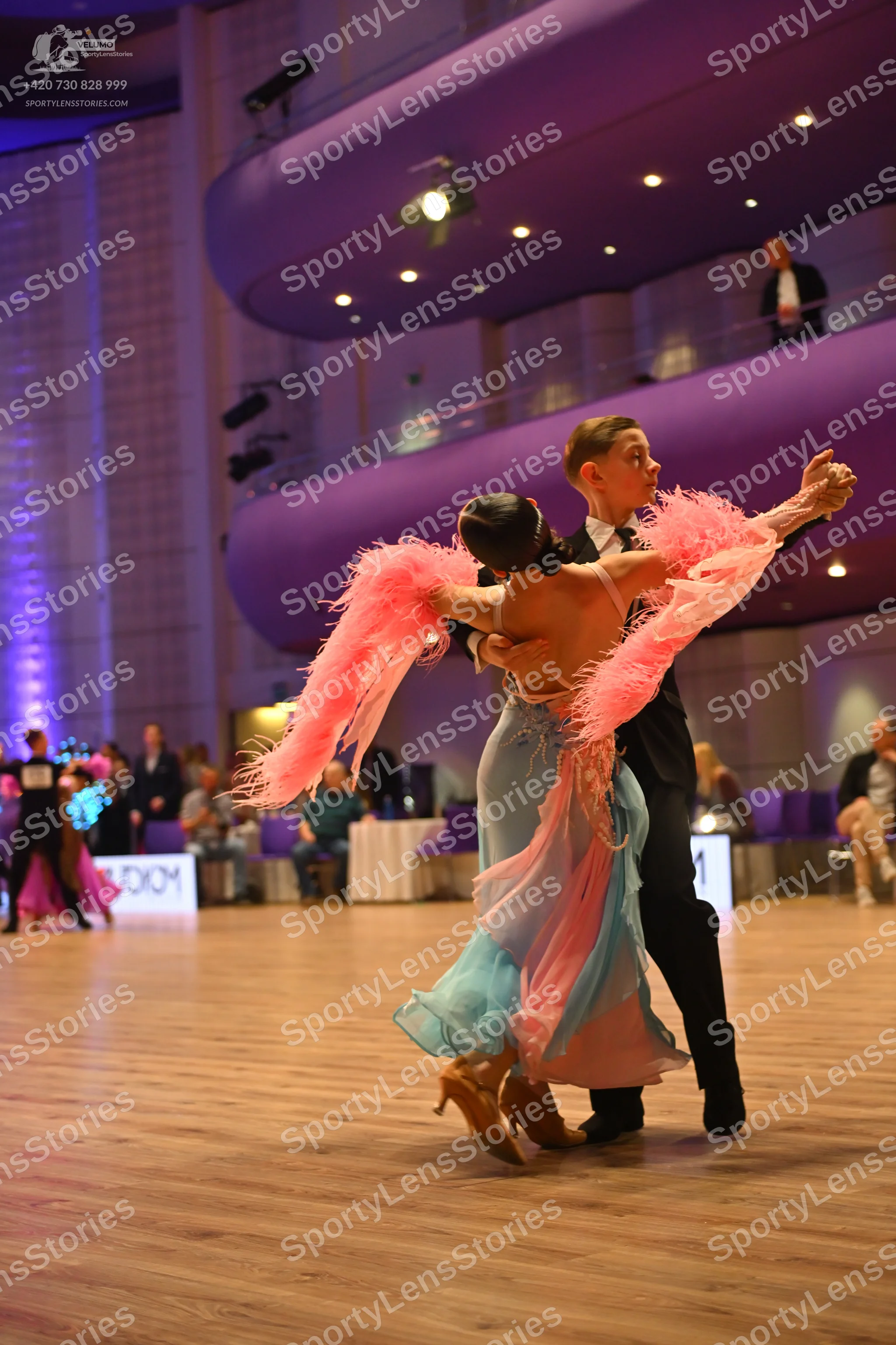 Dancesport competitor: Main female dancer: light blue/aqua backless dress with a flowing skirt and larg