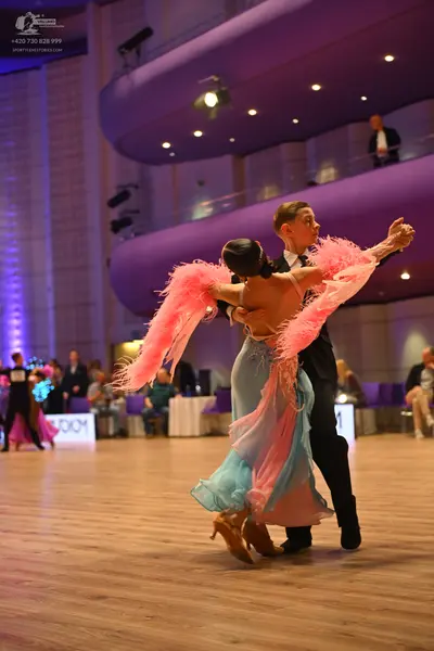 Dancesport competitor: Main female dancer: light blue/aqua backless dress with a flowing skirt and larg