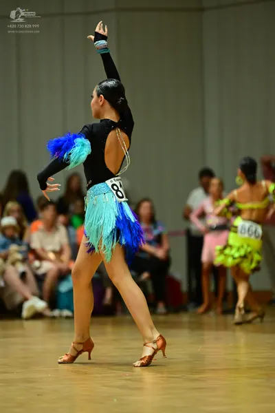 Dancesport competitor #84, #866: Female dancer (foreground): black long-sleeved Latin dance costume with an open 