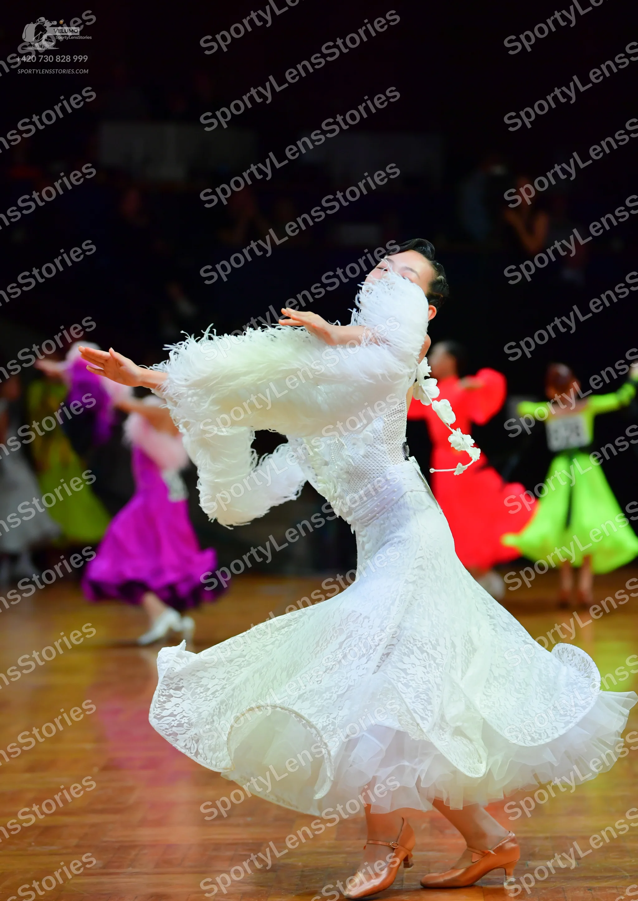 Dancesport competitor: Main dancer: white ballgown with large, voluminous, ruffled sleeves and lace-lik