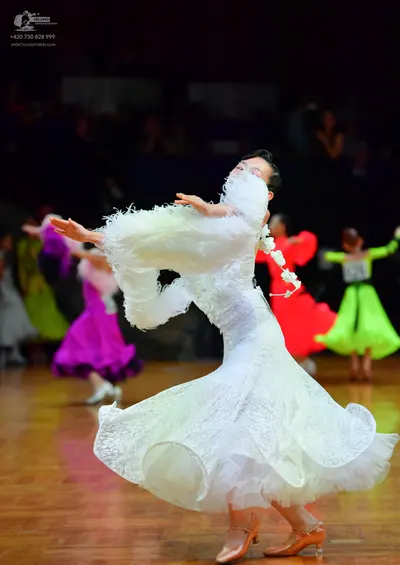 Dancesport competitor: Main dancer: white ballgown with large, voluminous, ruffled sleeves and lace-lik