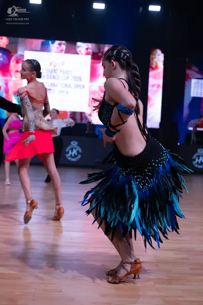 Dancesport competitor: Female dancer (foreground): black Latin dance dress with blue and teal sequins a