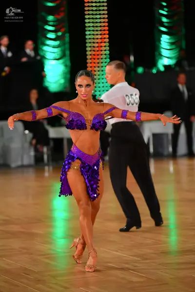 Dancesport competitor #355: Female dancer: purple sequined Latin costume including a bra-top, skirt, and arm