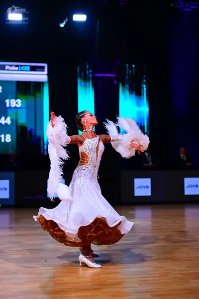 Dancesport competitor: Female dancer: white ballgown with gold sequin patterns on the bodice and a mult