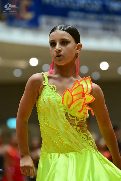 Dancesport competitor: ** Female: Lime green, sleeveless latin dress with a flared skirt and a large ru