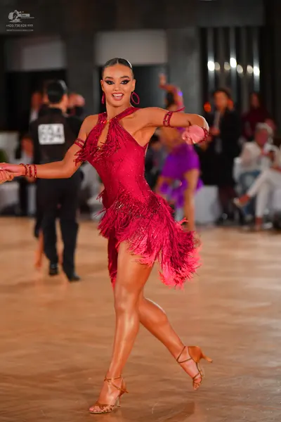 Dancesport competitor: Female dancer: red latin dress with fringe, pink hoop earrings, and red armbands