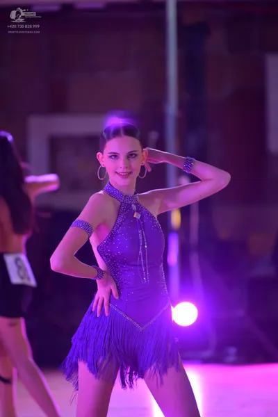Dancesport competitor: Female dancer in center: purple latin dance costume with sequins, fringe, halter