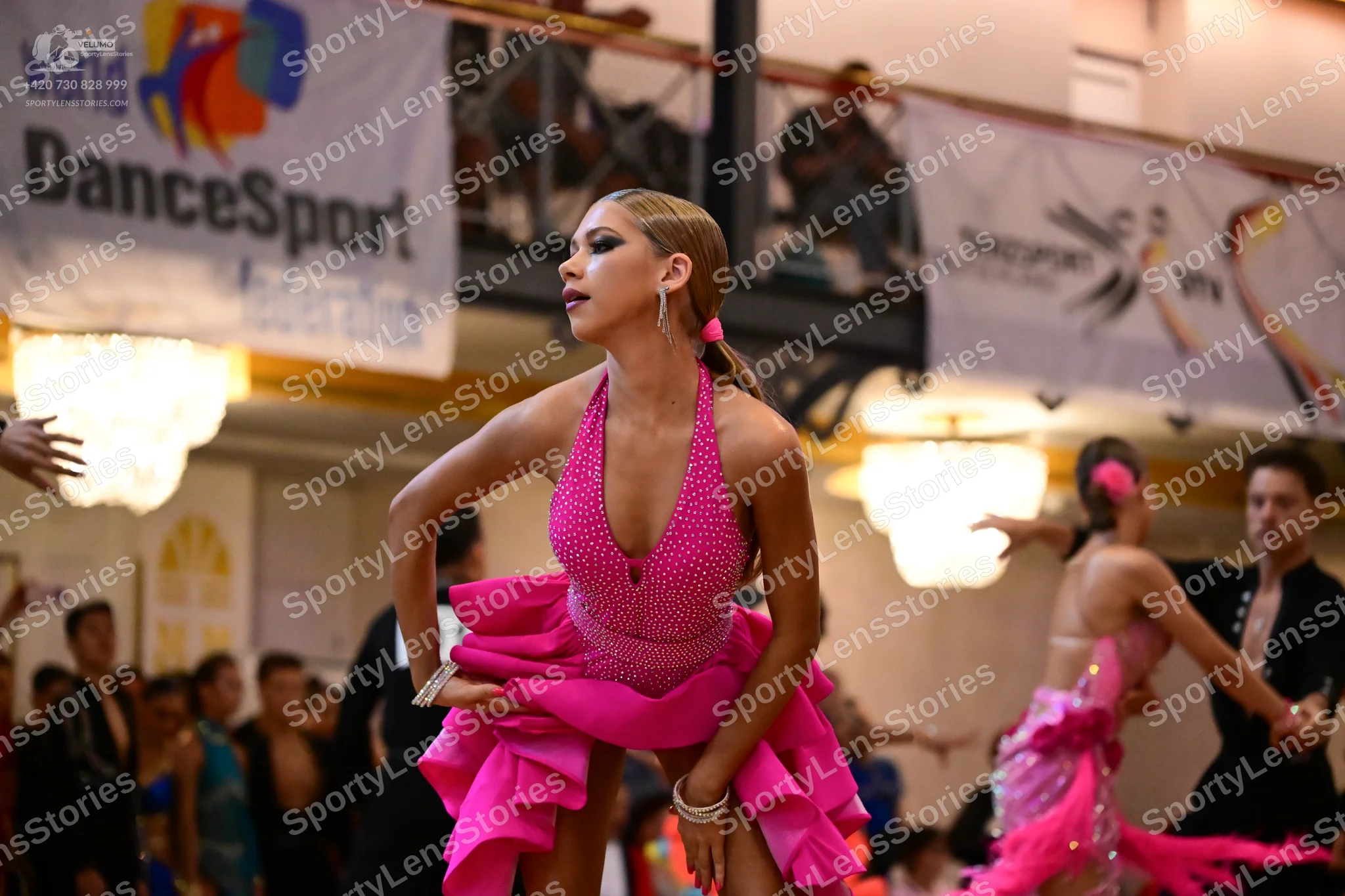 Dancesport competitor: Main female dancer: bright pink sequined Latin dress with a ruffled skirt and de