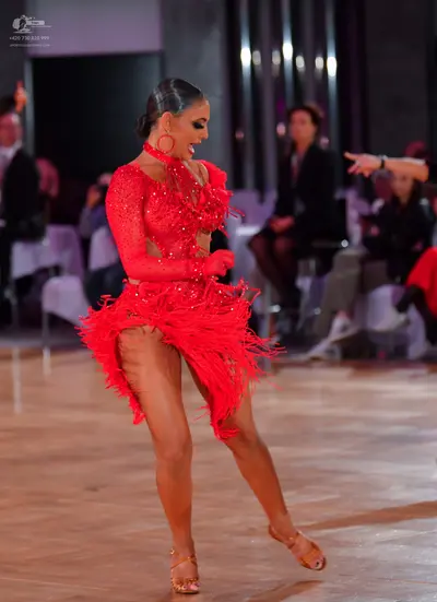 Dancesport competitor: Female dancer: red latin dress with long sleeves and fringe, red hoop earrings