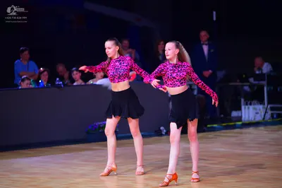Dancesport competitor: Female dancers: matching long-sleeved cropped tops with a pink and black pattern