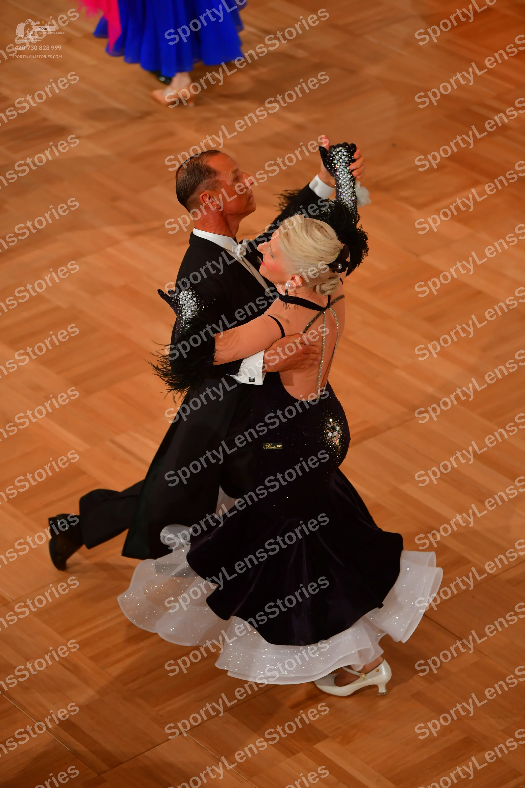 Dancesport competitor: Male dancer: black suit with black feathered or textured sleeve details and a wh