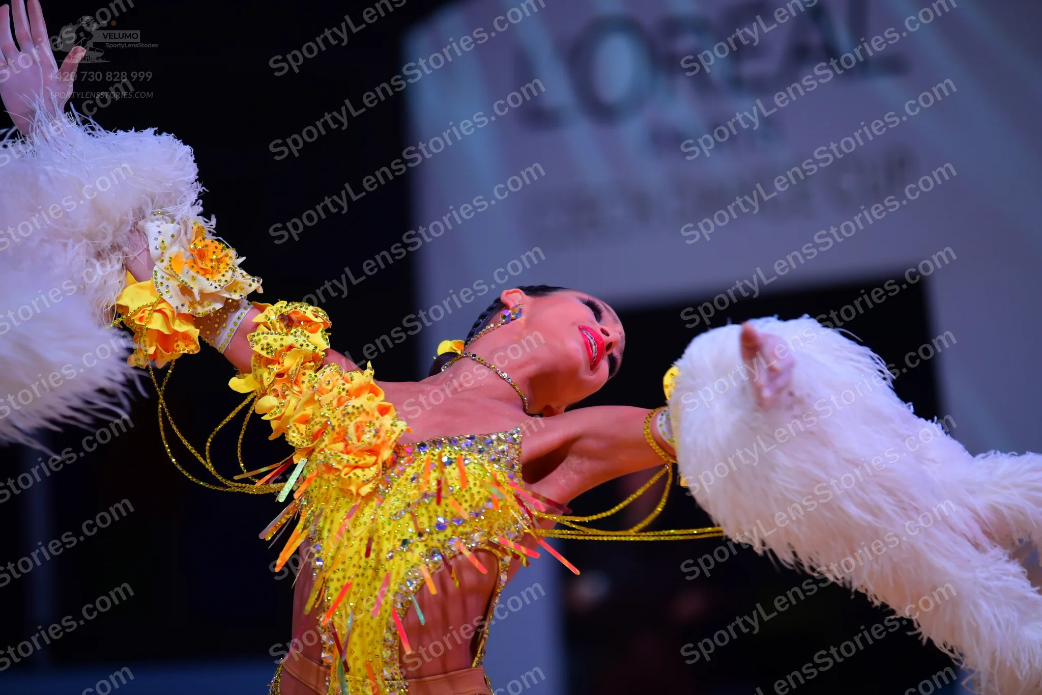 Dancesport competitor: Female dancer: bright yellow Latin dance dress with sequins, fringe, and large y