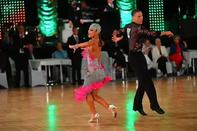 Dancesport competitor: Female dancer: silver/grey sequined Latin dress with bright pink fringe and a si