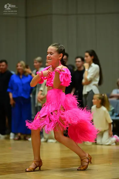 Dancesport competitor: Female dancer: bright pink latin dance dress with fringe and ruffled sleeves