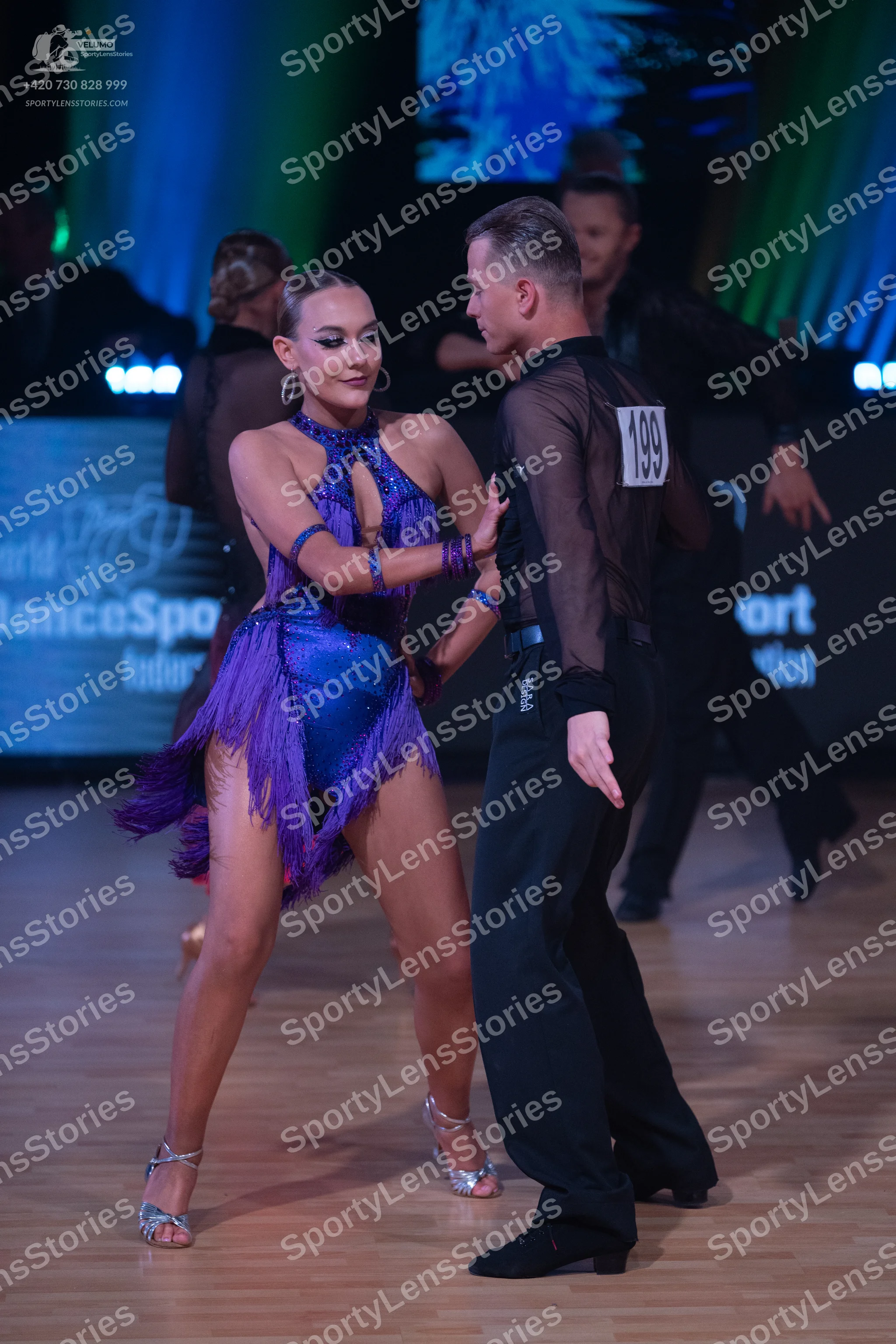 Dancesport competitor: Female dancer: purple Latin dress with a halter neck, shiny fabric, and long fri