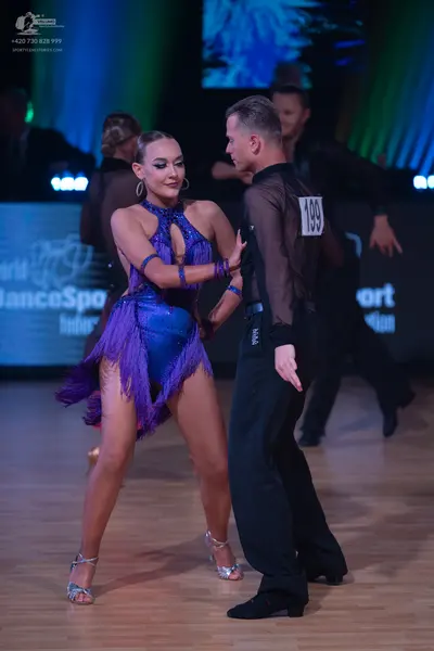 Dancesport competitor: Female dancer: purple Latin dress with a halter neck, shiny fabric, and long fri
