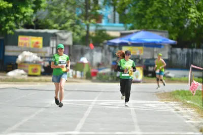 Marathon runner #518: Runner 1: green jersey, blue shorts, green cap, black shoes