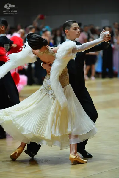 Dancesport competitor: Female dancer: cream-colored ballroom dress with a sequined bodice, a voluminous