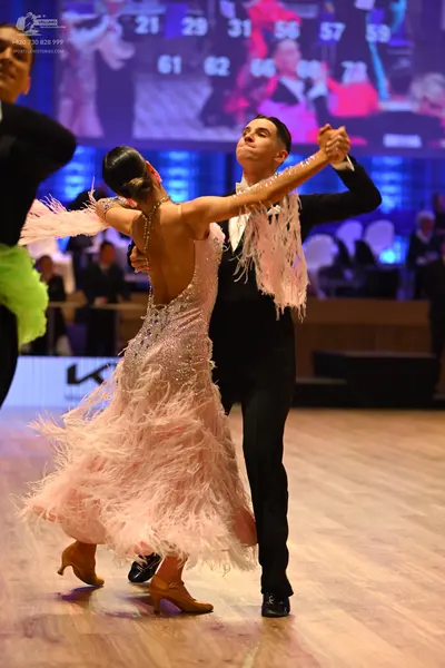 Dancesport competitor: Female dancer: light pink ballroom dress heavily embellished with sequins and fe