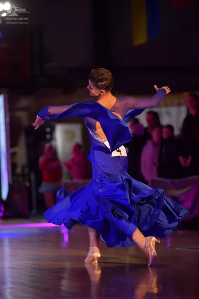 Dancesport competitor: Female dancer: royal blue ballgown with long sheer sleeves and a voluminous, ruf