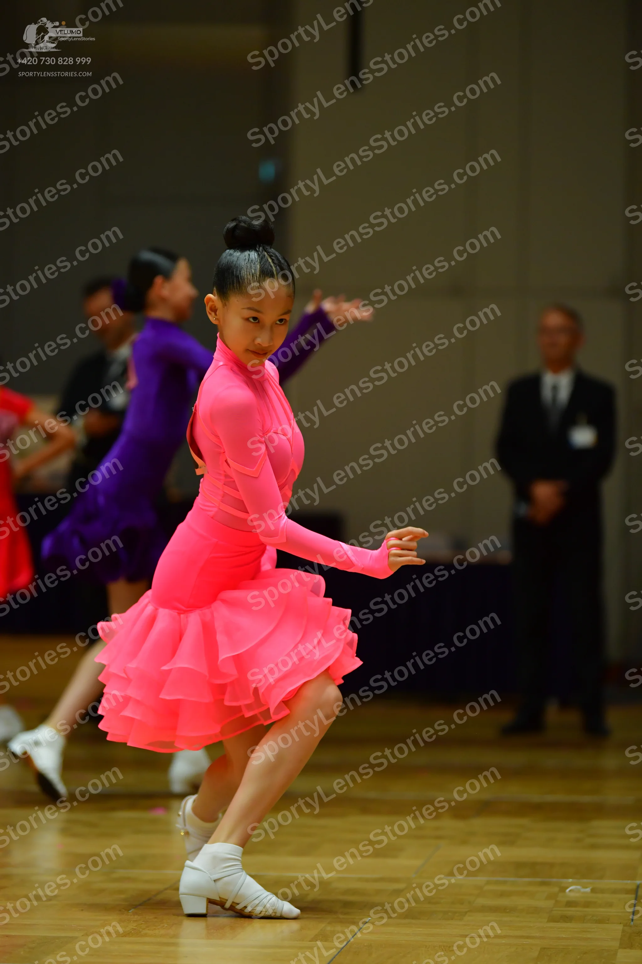 Dancesport competitor: Female dancer: bright pink, long-sleeved latin dress with a multi-layered ruffle