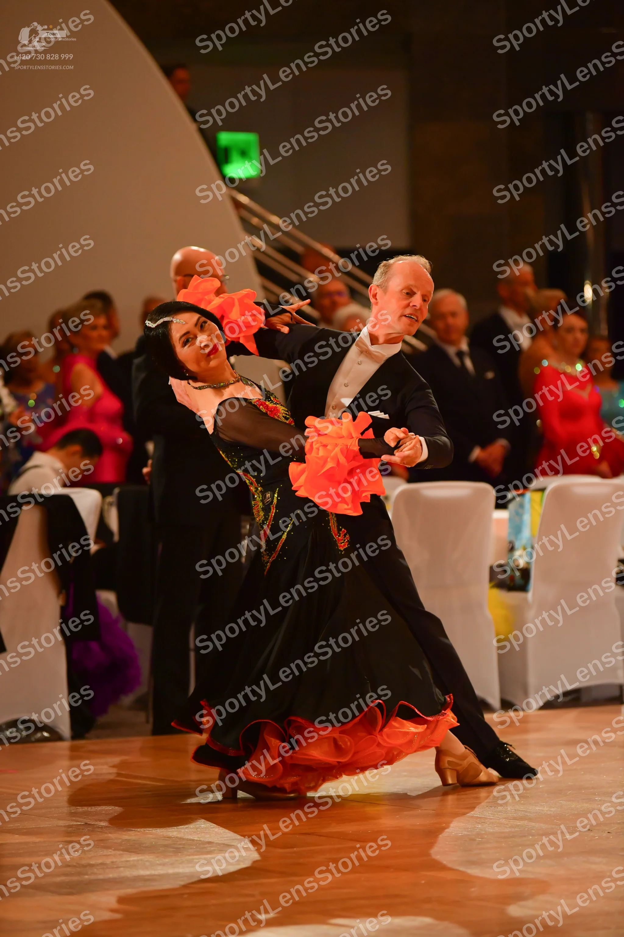 Dancesport competitor: Female dancer: black ballgown with large orange/peach ruffles at the hem and nec