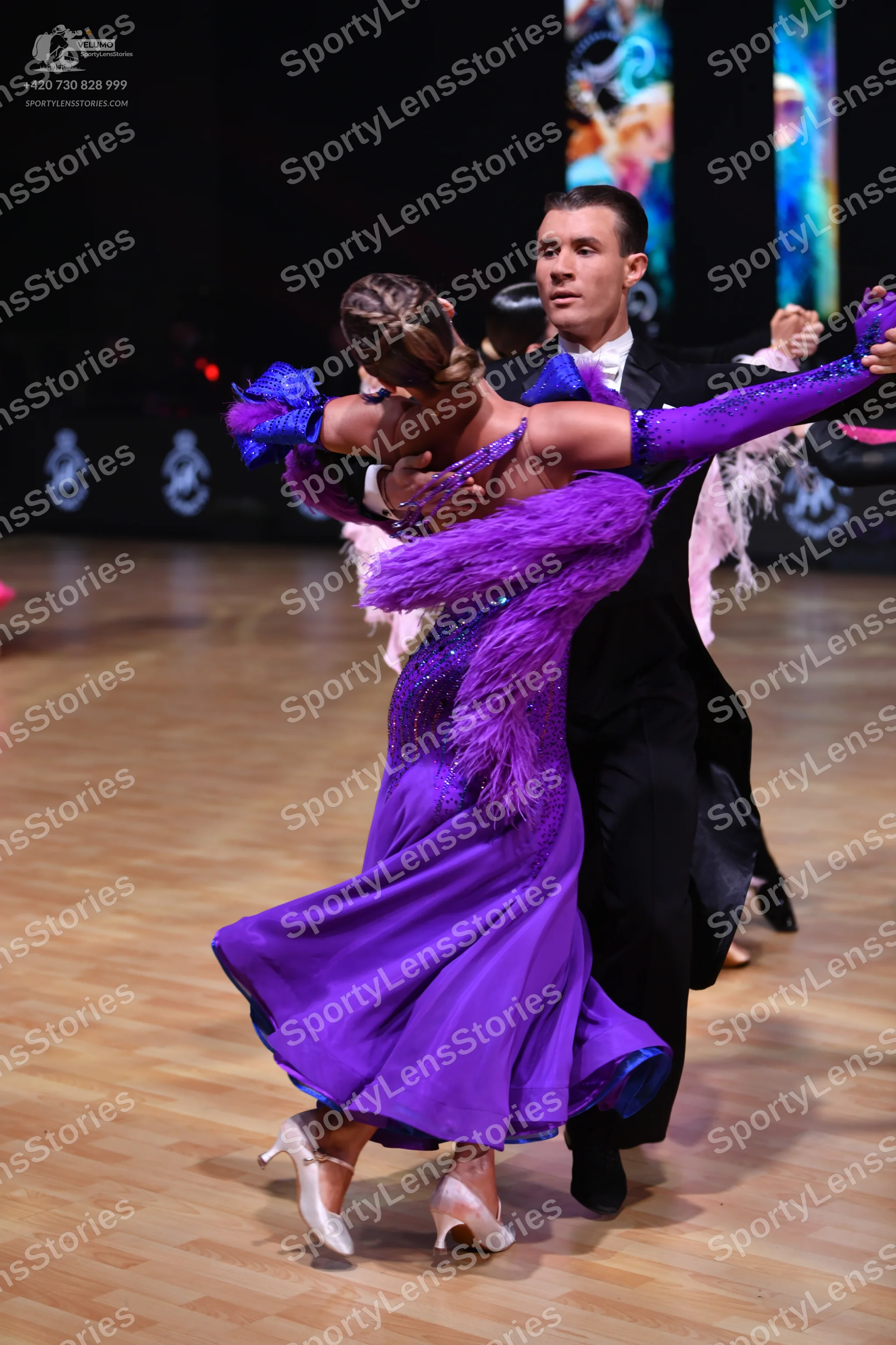 Dancesport competitor: Female dancer: purple sequined ballroom dress with large purple feather trim and